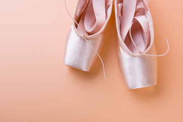 Top view of pink ballet shoes on yellow background