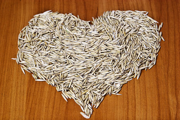 Heart of wheat grains on a wooden background close-up