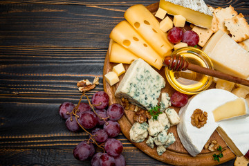 various types of cheese - brie, camembert, roquefort and cheddar on wooden board