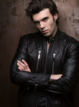 Portrait of a man in a black leather jacket near wall