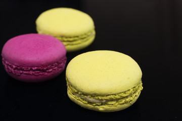 Macaroni cakes on black background. Close-up.