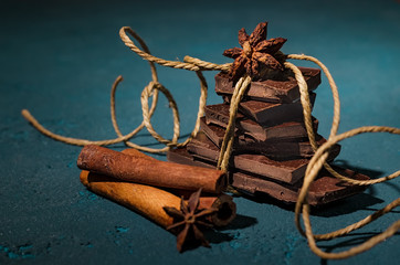Chocolate with cinnamon sticks on vintage blue background, selective focus