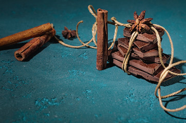 Chocolate with cinnamon sticks on vintage blue background, selective focus