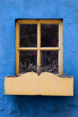 Close up detail of a yellow window on a blue house
