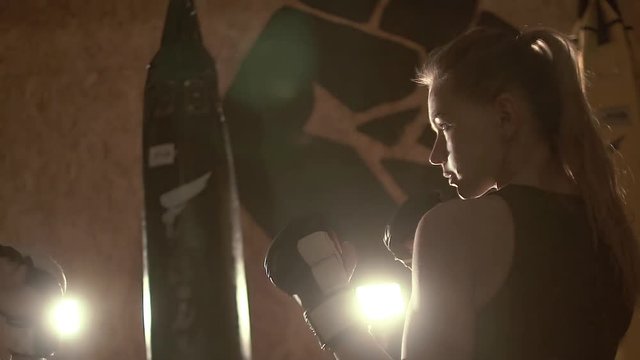 "Duel of views" of two girls kickboxers in front of a boxing match. The camera flies around. Slow motion