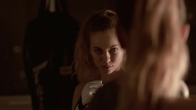 A beautiful kickboxer girl looks at the opponent in the eyes before the fight. Slow motion.