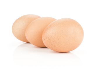 Three brown chicken eggs isolated on white background domestic in row.