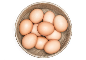 Brown chicken eggs in a wooden bowl top view isolated on white background.