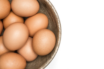 Brown chicken eggs in a wooden bowl isolated on white background top view.