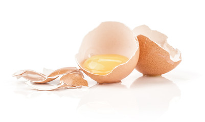 One raw yolk in a brown chicken eggshell two halves with a lot of cracked pieces isolated on white background.