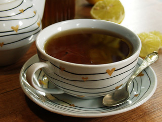 une tasse de thé chaud et fumant avec du miel et du citron, une théière