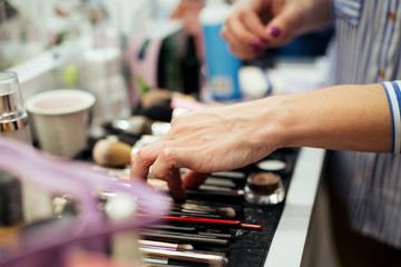 Obraz na płótnie Canvas Female makeup artist with cosmetics at work close-up