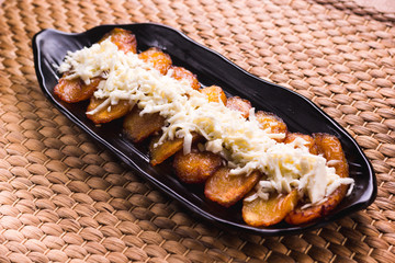 Fried plantain with cheese striped on top, South American food © nehopelon