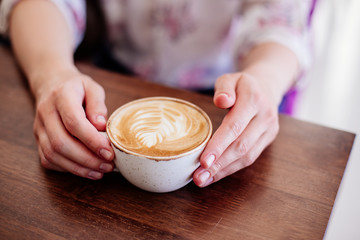 Cup of cappuccino in hands.