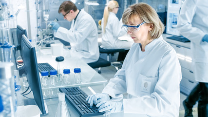 High Tech Ultra Modern Laboratory with Scientists Conducting experiments, Working on Computers, Looking at Substance under Microscope and Mixing Chemicals.