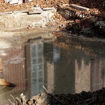 Reflection in an excavation pit with groundwater on which a thick, greasy layer of heating oil floats