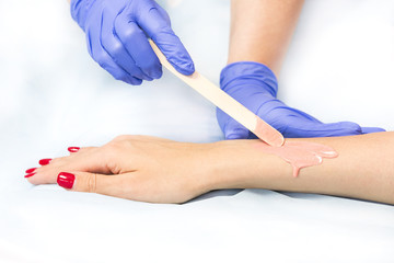 The process of classical wax depilation of female limbs in the beauty salon. 