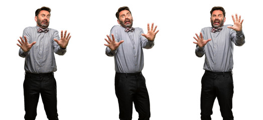 Middle age man, with beard and bow tie disgusted and angry, keeping hands in stop gesture, as a defense, shouting