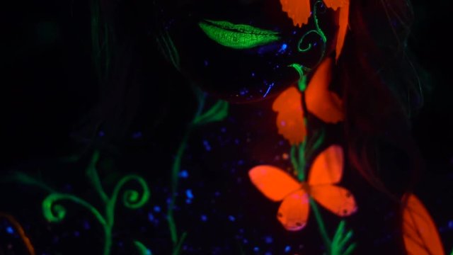 A girl with green lips and orange butterflies on her body sexually bites her lip