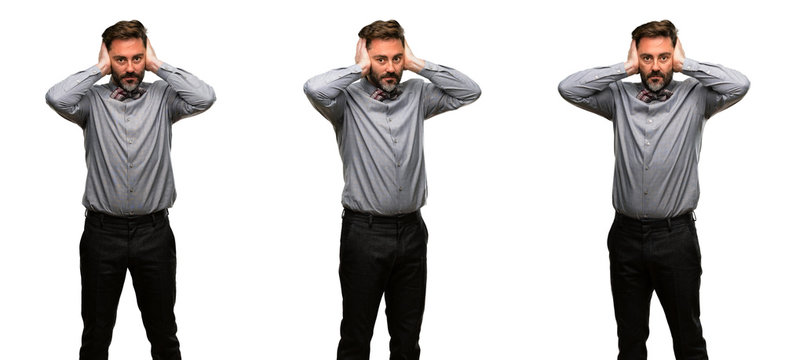 Middle age man, with beard and bow tie covering ears ignoring annoying loud noise, plugs ears to avoid hearing sound. Noisy music is a problem.