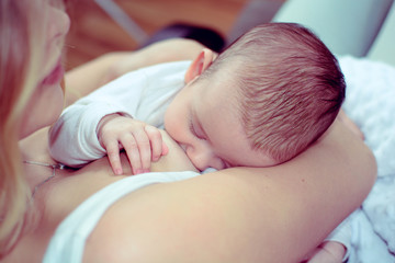 Breastfeeding baby close up. Pretty mother holding her newborn child. Mom nursing sleeping baby. Beautiful woman and new born relax at home. Blondе mother breast feeding baby.