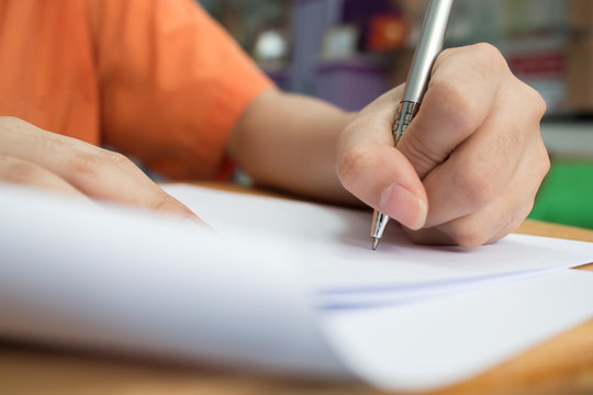 School Students hands taking exams, writing examination room with holding pencil on optical form of standardized test with answers and english paper sheet on desk doing final exam in classroom.