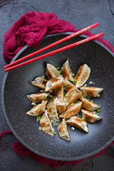 Fried gyoza dumplings in a wok pan, vertical shot, selective focus, above view