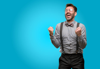 Fototapeta premium Middle age man, with beard and bow tie happy and excited expressing winning gesture. Successful and celebrating victory, triumphant