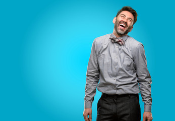 Middle age man, with beard and bow tie confident and happy with a big natural smile laughing