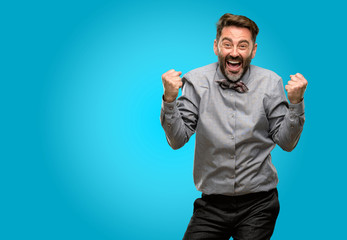 Fototapeta premium Middle age man, with beard and bow tie happy and excited celebrating victory expressing big success, power, energy and positive emotions. Celebrates new job joyful