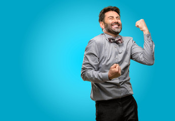 Middle age man, with beard and bow tie happy and excited celebrating victory expressing big success, power, energy and positive emotions. Celebrates new job joyful