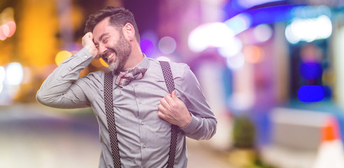 Middle age man, with beard and bow tie confident and happy with a big natural smile laughing at night club