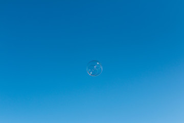 Soap bubble against a bright and clear blue sky