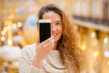 Young beautiful girl showing your smart phone screen