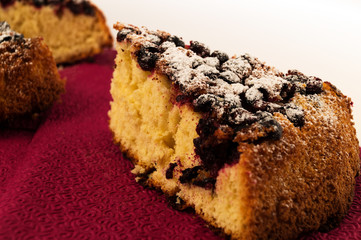 A slice of homemade baking with berries on a bard napkin on a white background.