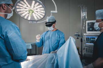 Group of surgeons using augmented reality holographic hololens glasses while operating in modern operation theater