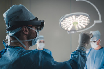 Surgeon using augmented reality holographic hololens glasses while operating in modern operation...