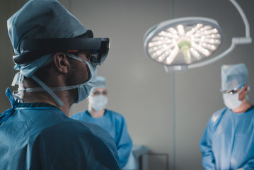Surgeon using augmented reality holographic hololens glasses while operating in modern operation...