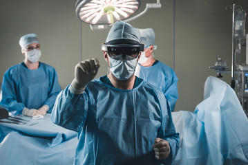 Group of surgeons using augmented reality holographic hololens glasses while operating in modern operation theater