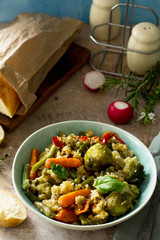 Healthy dietary vegan dish: couscous and vegetables (string beans, brussels sprouts, carrots, sweet peppers, tomatoes) on a stone or slate background.