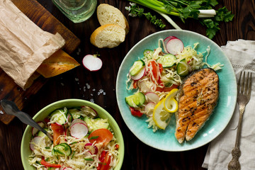 Grilled salmon steak and vegetarian vegetable salad of radish, cucumbers, lettuce salad. Healthy proper nutrition. Top view.
