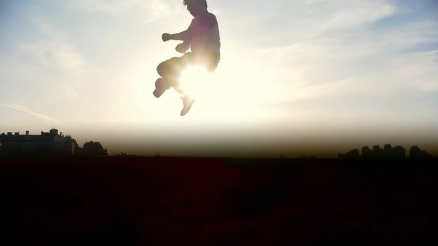 Slow-motion - young male Parkour tricker jumper performs amazing flips in front of the sun