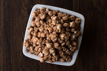 Chocolate Popcorn on dark Wooden Surface.