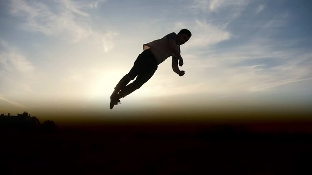 Man Parkour tricker jumper performs amazing flips, silhouette