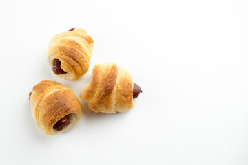 Home made pigs in a blanket. Sausages rolled in croissant dough baked and placed On white background.