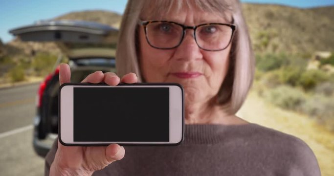 Somber Looking Old Woman Pulled Over On Desert Road With No Service On Phone, White Female Holding Up Phone With No Service Warning Flashing On Phone Display, 4k