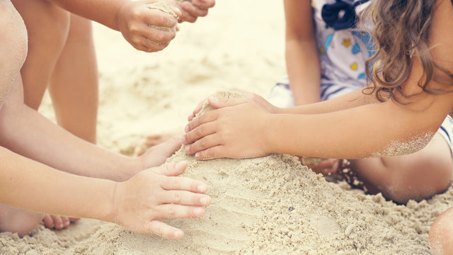 Group of little children build a sand tower, hands closeup