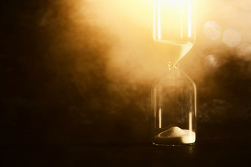 Image of hourglass as time passing concept over black background for business deadline. Glitter overlay.