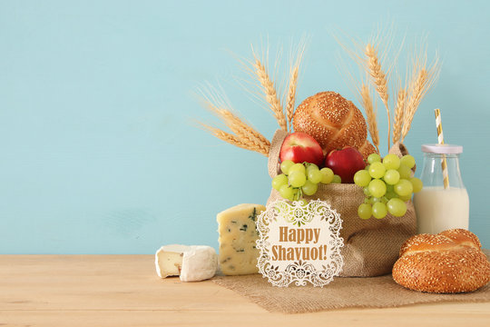 image of fruits, bread and cheese in the basket over wooden table.
