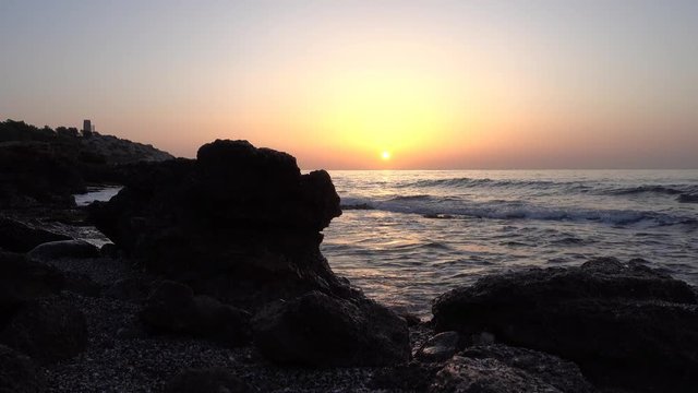 Golden sunrise on a beach next to the rocks